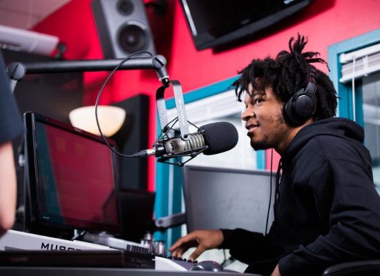 male student working in a radio station booth